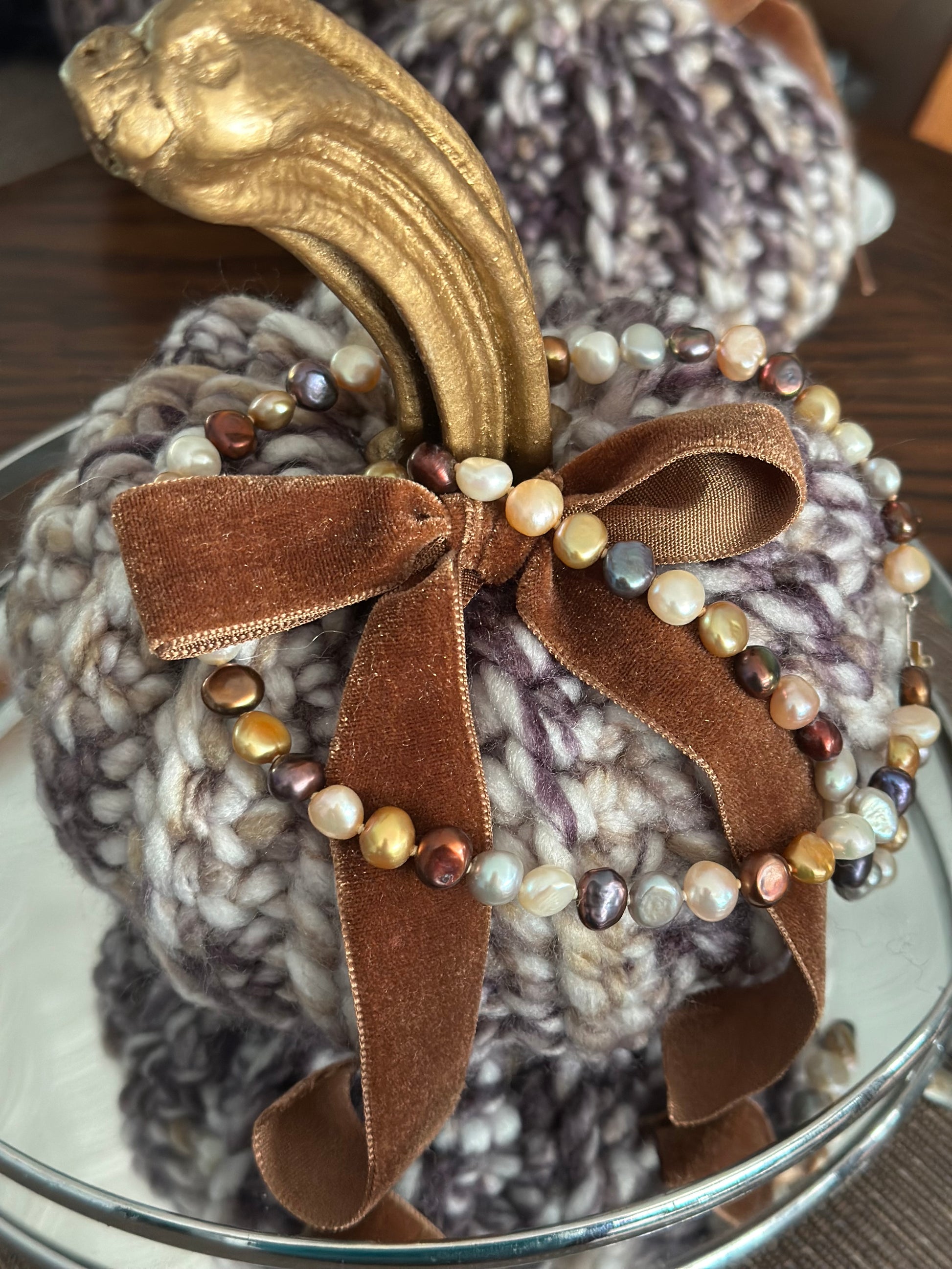 Decorative pumpkin with brown velvet ribbon and beads on a textured surface
