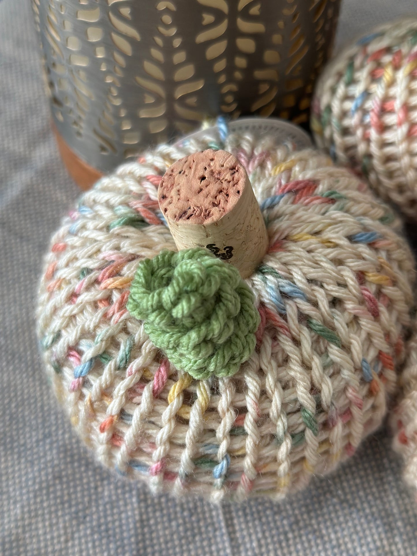 Knitted yarn pumpkin with a green tendril on a textured surface
