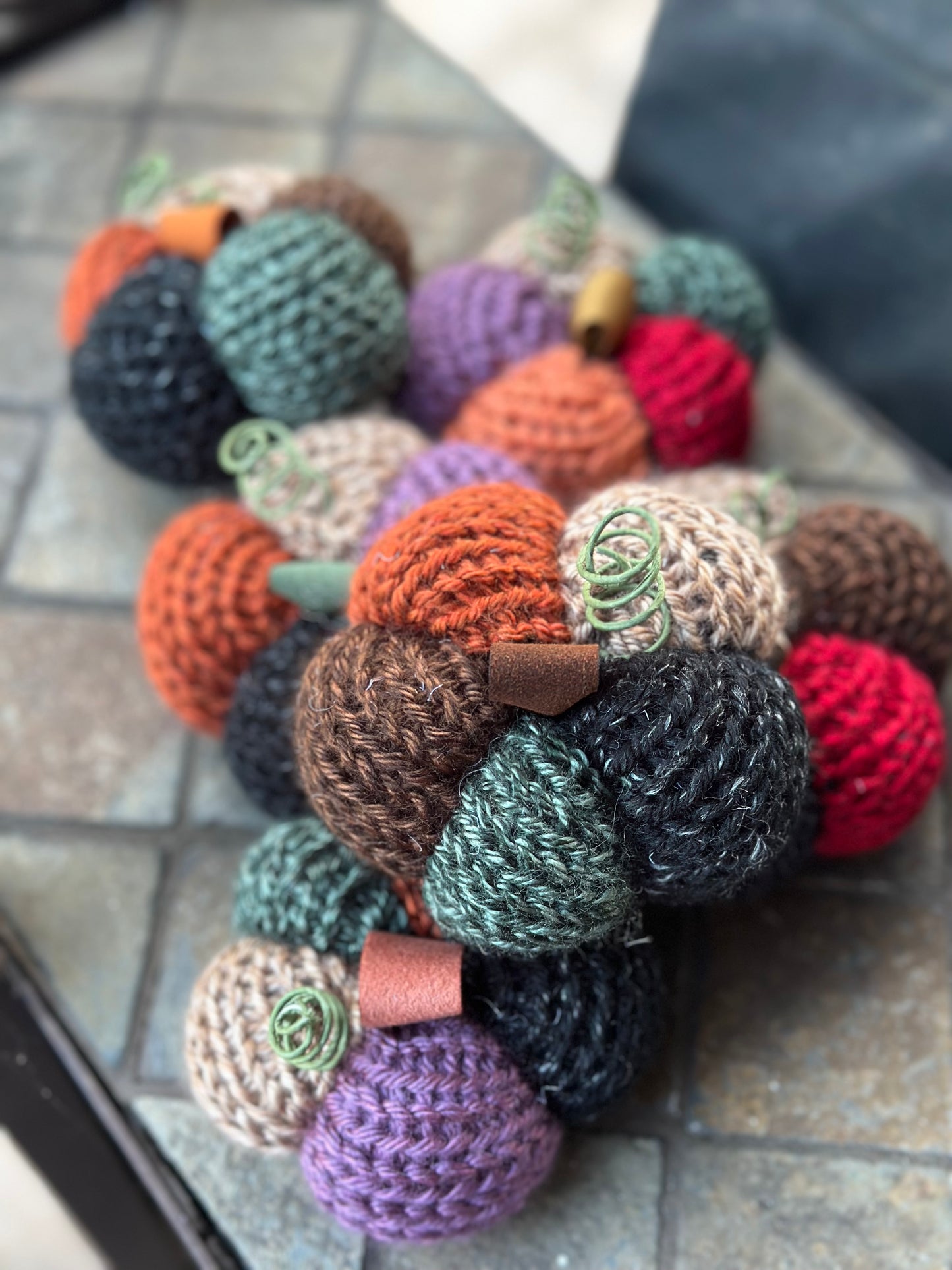 Colorful knitted daisy-shaped pumpkins on a tiled surface