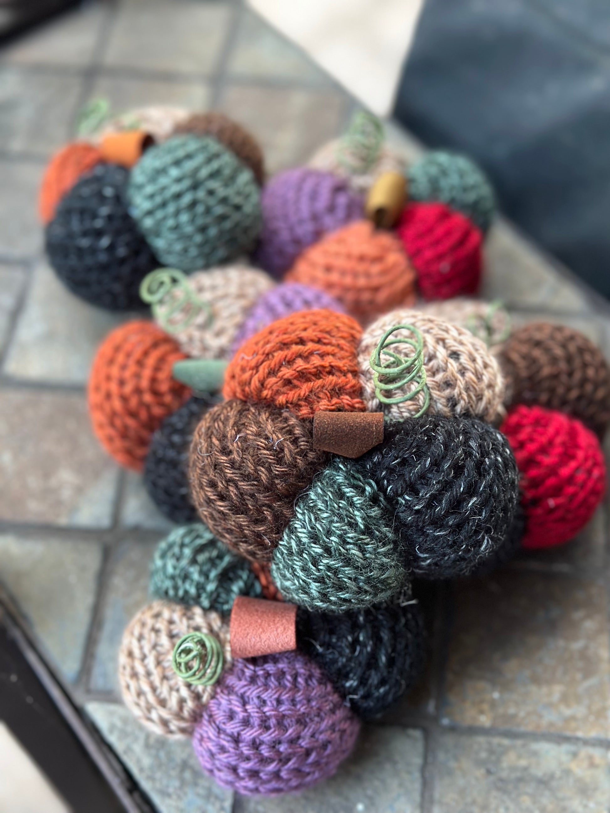Colorful knitted daisy-shaped pumpkins on a tiled surface