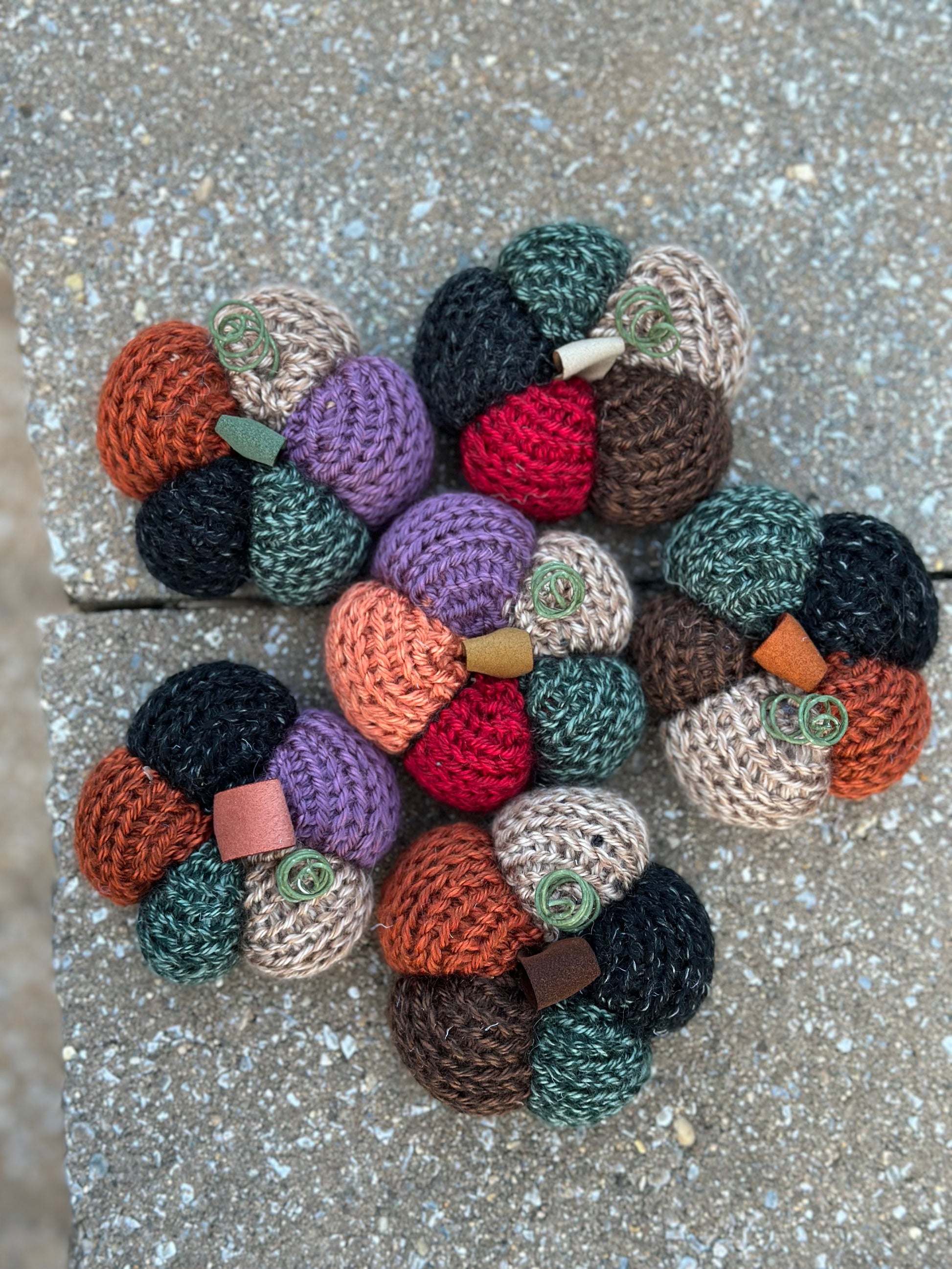 Colorful knit pumpkin decorations on a concrete surface