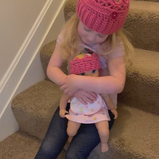 video showing little girl holding a doll with matching crowns.