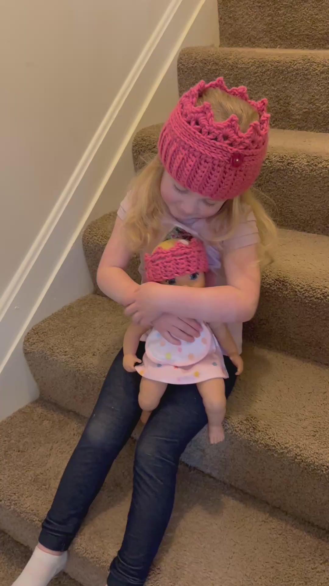 video showing little girl holding a doll with matching crowns.