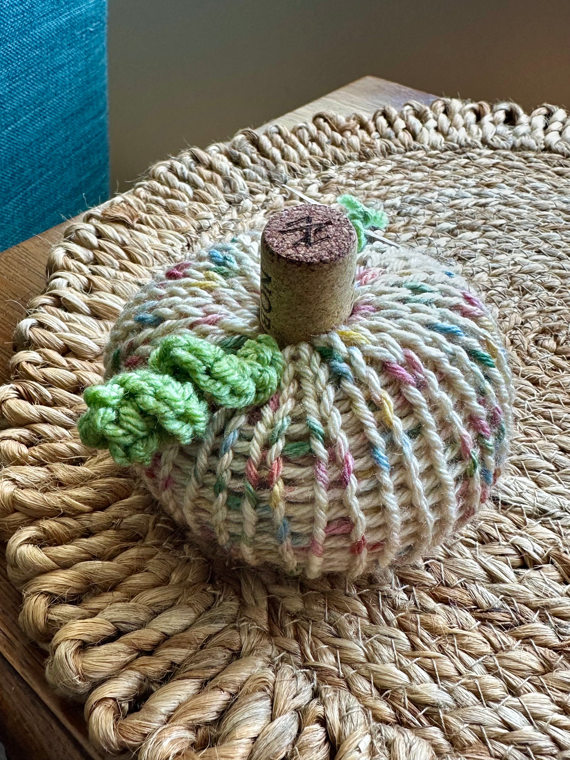 Knitted pumpkin decoration on a woven surface