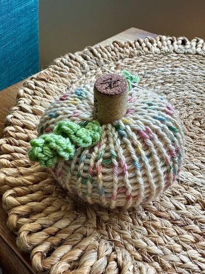 Knitted pumpkin decoration on a woven surface